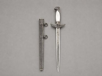 une vieille dague et un couteau posés sur une surface grise