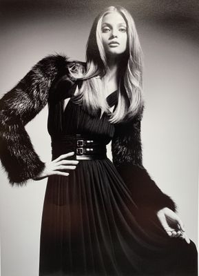 photographie en noir et blanc d'une femme vêtue d'une robe noire et d'un manteau de fourrure