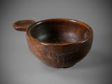 an old wooden bowl with a wooden spoon on a gray surface