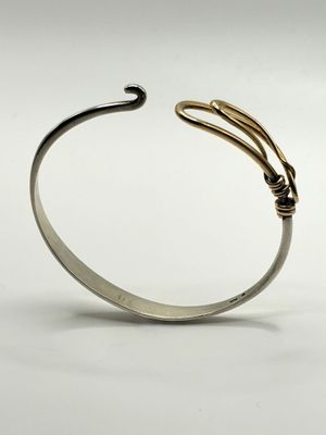 a close up of a silver cuff with a gold snake on it