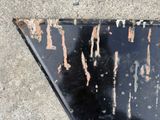 a black triangle with rust on it sitting on the sidewalk