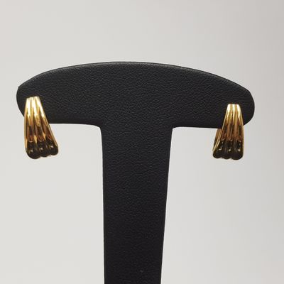 une paire de boucles d'oreilles dorées posées sur un support noir