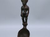 une statue en bronze représentant une femme tenant un bébé sur une cuillère