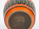 an orange vase with black writing on it on a white surface