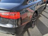 the rear end of a black car parked in a parking lot