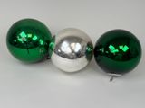 trois décorations de Noël vertes et argentées brillantes posées sur une surface blanche