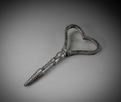 an old key shaped like a heart on a gray background