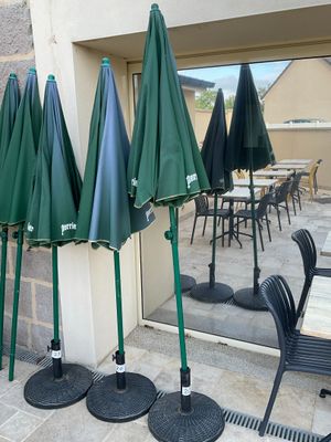 Plusieurs parapluies verts sont alignés à l'extérieur d'un immeuble