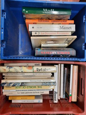 une pile de livres dans une boîte en plastique posée sur une étagère