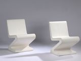 two white chairs sitting next to each other on a white surface