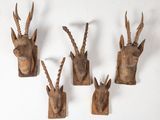 four wooden antelope heads mounted on a white wall