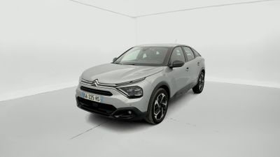 Une voiture argentée est garée dans une pièce blanche au sol blanc.
