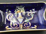 a blue and yellow plate with a vase and flowers on it