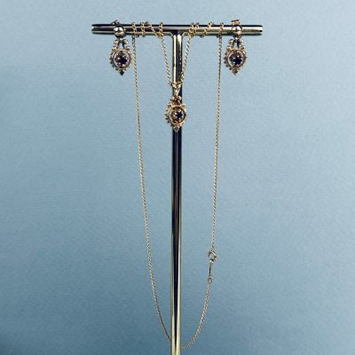 un présentoir à colliers en argent et en or, duquel pendent trois chaînes