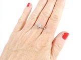 a woman ' s hand with a red manicure holding a diamond ring