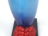 a blue vase with a black base and a black and white dog on top