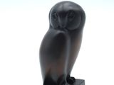 an image of a black owl statue sitting on top of a wooden block