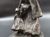 bronze statue of a woman holding a child on a rock