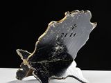 a black and gold leaf shaped clock on a white table
