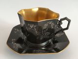 a black and gold tea cup and saucer on a saucer