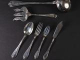 a lot of silver spoons and forks on a black table