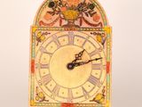 a clock that is sitting on a stand on a white surface