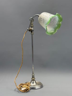 une lampe à l'ancienne avec un abat-jour en verre vert et une chaîne dorée