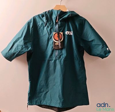 a green jacket hanging on a hanger on a wall