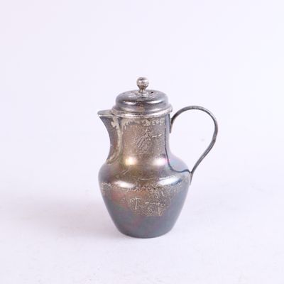 une cafetière en argent posée sur un plan de travail blanc