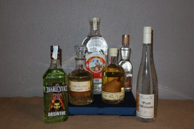 Des bouteilles d'alcool sont alignées sur une table, à côté d'une bouteille de vin