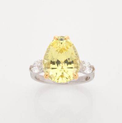 a close up of a yellow and white diamond ring on a white surface