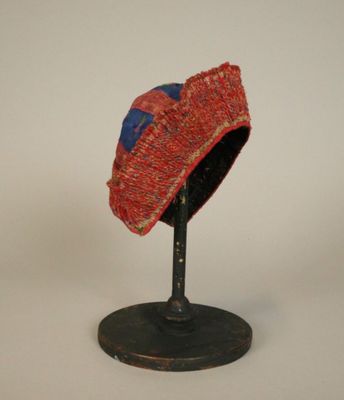 un chapeau rouge et bleu posé sur un socle noir