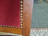 the back of a red chair with gold beads on it