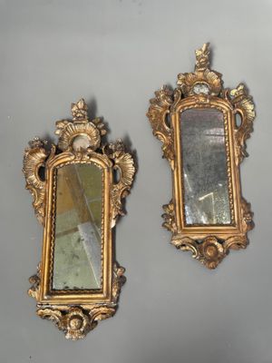 two mirrors hanging on the wall next to each other