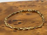 a close up of a gold bracelet on a wooden surface
