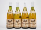 quatre bouteilles de vin sont alignées sur une surface blanche