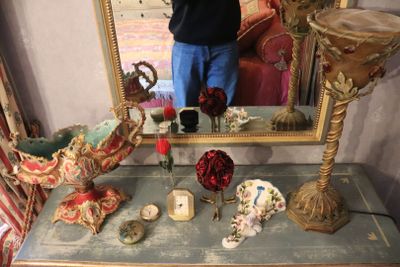 a man taking a picture of a table with a mirror and vases on it