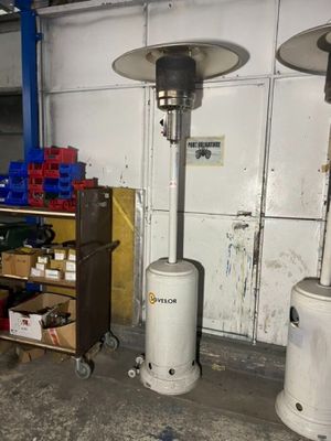 trois chauffages à gaz dans un garage où se trouve un chariot rempli de cartons