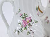 two white vases with pink flowers painted on them