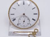 une petite montre de poche blanche avec une clé, posée sur un socle