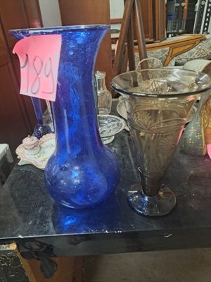 un vase en verre bleu posé sur une table, à côté d'autres objets en verre