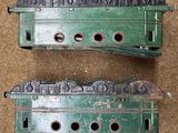 two green train engines sitting side by side on the ground