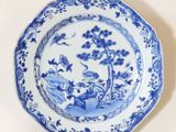 a blue and white plate with a bird and flowers on it