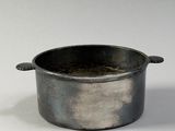a small metal pot with a handle on a white surface