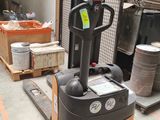 a fork lift truck in a warehouse with other items in the background