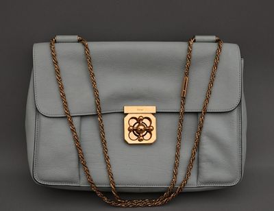 un sac à main gris muni d'un fermoir doré attaché à une chaîne