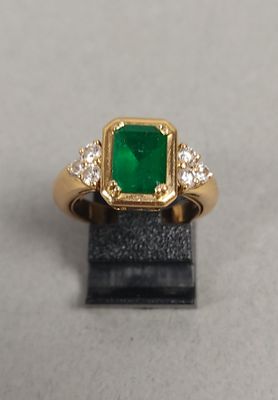 gros plan d'une bague avec une pierre verte entourée de diamants blancs