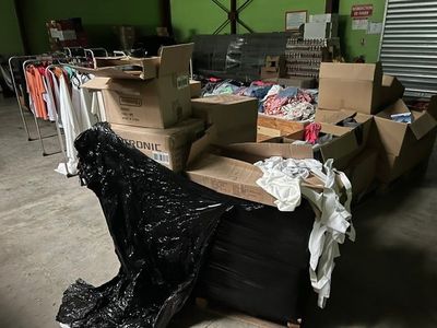 une pile de cartons et de vêtements posée sur un carton dans un entrepôt
