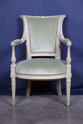 une vieille chaise dont l'assise est recouverte d'un tissu vert sur fond bleu