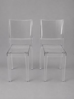 une paire de chaises en plastique transparent sur fond gris